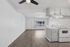 Bright and open living space with modern laminate flooring, sleek ceiling fan, and an inviting kitchen area ideal for cozy gatherings.