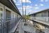 Charming apartment complex courtyard with elegant iron railings and lush palm trees under a bright blue sky.