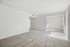 Bright and spacious living area with plush carpet, crisp white walls, and large windows offering ample natural light.