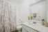 Elegant bathroom featuring a modern sink, decorative plants, and a stylish shower curtain with a tropical theme.