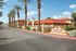 Charming Toscana Villas apartment complex with palm-lined driveway and attractive red tile roofing, offering serene living in a beautiful setting.