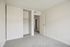 Bright bedroom with fresh carpet, sleek white walls, and a spacious sliding closet for modern living.