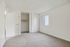 Bright and spacious bedroom with fresh carpeting, large closet, and natural light from a window with vertical blinds.