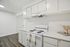 Charming kitchen boasting sleek white cabinets, modern black stove, and elegant wood flooring, exuding a bright and inviting ambiance.