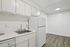 Bright, modern kitchen with sleek white cabinetry, stainless steel sink, and a spacious refrigerator.