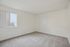 Bright and spacious room with soft carpeting and a large window, featuring modern, minimalist design. Ideal for creating a cozy bedroom or a serene home office.