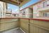 Charming apartment balcony offering a cozy outdoor space with views of elegant architecture and bright sky.