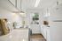 Bright, modern kitchen with sleek white cabinetry, polished countertops, and a scenic window view.