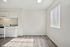 Bright modern kitchen area with sleek white cabinets, elegant countertops, and beautiful natural light through vertical blinds.