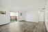 Bright and spacious living area with elegant wood flooring, large sliding doors, and a private balcony, ideal for modern living.