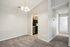 Bright apartment interior featuring a cozy carpeted dining area with elegant overhead lighting, adjacent to a modern kitchen and a sunlit hallway leading to bedrooms.