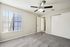 Bright and inviting bedroom with plush carpet, a large window, and a ceiling fan offering comfort and elegance.