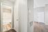 Bright apartment entrance featuring modern flooring, fresh paint, and a welcoming hallway leading to a stylish bathroom.
