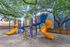 Charming playground with vibrant slides and climbing structures nestled under lush trees, perfect for family fun and outdoor enjoyment.
