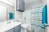 Bright and modern bathroom featuring a sleek white countertop, stylish silver fixtures, and a vibrant striped shower curtain for a fresh, inviting atmosphere.