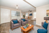 Bright and inviting living room with virtual staging, featuring cozy gray armchairs and vibrant blue cushions, complemented by a modern wooden coffee table and sleek dining area.