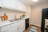Chic galley kitchen with modern black appliances, elegant white cabinetry, and stylish wooden flooring, perfect for a cozy culinary experience.