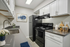 Chic, virtually staged kitchen featuring modern white cabinetry, sleek black appliances, and elegant decor.