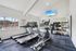 Bright and modern fitness center with treadmills, elliptical, and a variety of exercise equipment set against a sleek mirror wall.