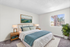 Bright and inviting bedroom featuring a cozy bed with elegant blue and white bedding, large window with natural light, modern lamps on wooden nightstands, and a potted plant for fresh ambiance.