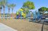 Vibrant playground featuring colorful climbing structures surrounded by lush palm trees, perfect for family fun and outdoor enjoyment.