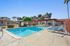 Inviting outdoor pool area with luxurious lounge chairs, vibrant red-roofed buildings, and lush greenery perfect for relaxation and enjoyment.