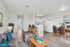 Virtually staged modern living space featuring a cozy gray sofa with blue cushions, a sleek kitchen with white cabinets, and a stylish dining area with gray chairs and wooden table.