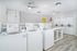 Modern and inviting laundry room with multiple washing machines, bright lighting, and a clean, spacious layout.