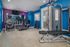 Modern fitness center with vibrant blue and purple walls, featuring state-of-the-art treadmills, weight machines, and free weights.