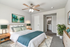 Elegant bedroom with modern ceiling fan, plush bedding, and tasteful decor, featuring a cozy rug and vibrant artwork, offers a serene and stylish retreat.