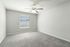 Bright and spacious bedroom with soft carpeting, modern ceiling fan, and ample natural light through a large window.