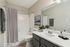 Modern bathroom with elegant decor, featuring a sleek white countertop, lush greenery, and stylish artwork by the tub.