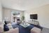 Bright and inviting living room with modern furniture, sleek TV setup, and large window offering scenic views.