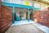 Charming patio entrance with vibrant teal accents, a cozy seating area, and rustic wooden fencing.