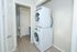 Modern laundry area featuring a sleek stacked washer and dryer, set against a stylish gray wood floor, perfect for convenient apartment living.