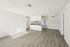 Bright, open-concept living area with modern kitchen, hardwood floors, and ceiling fan.
