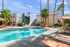 Inviting apartment complex with palm trees and a shimmering swimming pool, offering a relaxing outdoor escape.