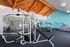 Bright and modern fitness center with state-of-the-art equipment, featuring a warm wooden ceiling and vibrant turquoise walls.