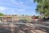 Inviting community dog park featuring agility equipment, fenced area, and serene surroundings under a clear blue sky.