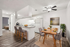 Brightly staged dining and kitchen area featuring elegant seating, modern appliances, and tasteful decor with a glimpse into a cozy bedroom.