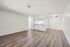 Modern open-concept living area with sleek hardwood flooring, a bright white kitchen with appliances, and a ceiling fan for comfort.