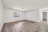 Bright and spacious apartment living area with modern laminate flooring, fresh white walls, and a large window for natural light.