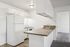 Bright, modern kitchen with sleek granite countertops, white cabinets, and appliances, leading to a cozy carpeted room.