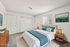 Elegant and inviting bedroom with plush teal and white bedding, warm wood furnishings, modern decor, and ample closet space, showcasing virtual staging at its finest.