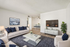 Elegantly staged living room with plush white sofas, navy cushions, and a sleek modern coffee table on a cozy gray rug. Wall-mounted TV and stylish decor create a serene ambiance.