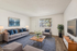 Modern living room with stylish decor, featuring a comfortable sofa, cozy armchair, decorative plant, and wall-mounted TV, ideal for relaxation and entertaining.