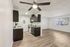 Modern apartment interior featuring a sleek open-plan kitchen and living area with stylish dark cabinetry, bright overhead lighting, and spacious wood-style flooring.