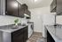 Modern kitchen with sleek dark cabinetry, sparkling countertops, and stainless steel appliances, featuring cozy dining setup.
