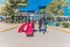 Bright and inviting playground area with a colorful slide and climbing structures, nestled amidst lush greenery and modern apartments.