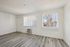 Bright and airy living space with modern light wood flooring, two large windows allowing natural light, and a sleek air conditioning unit.